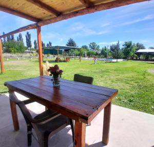 een houten picknicktafel met een vaas met bloemen erop bij Cabaña LuMa in San Rafael