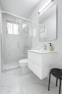 a white bathroom with a shower and a toilet and a sink at Limassol Centr Apartament in Limassol