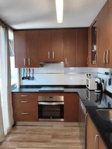 Una cocina con gabinetes de madera y un horno de estufa. en House atarfe ii motril, en Atarfe