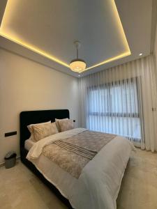 a bedroom with a large bed with a large window at Appartement modern a malabata hills in Tangier