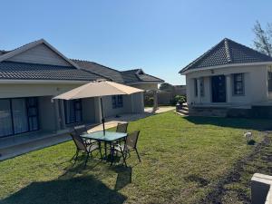 een tafel en stoelen met een parasol in de tuin bij WeMvula Guesthouse in Mtubatuba