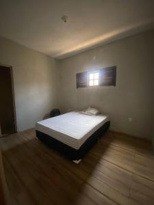 een slaapkamer met een bed in een kamer met een raam bij Casa imperr in Aracati +3 foto's
