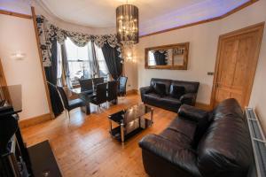 a living room with a leather couch and a dining room at Roomy home 1 level Free Parking in Edinburgh