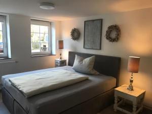 a bedroom with a bed with two lamps and two windows at Landhaus am Schlosspark FeWo 4 in Brakel