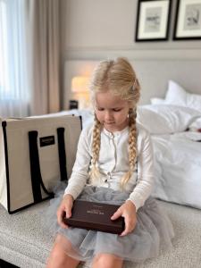 a little girl sitting on a bed holding a laptop at The Bristol Belgrade in Belgrade +88 photos