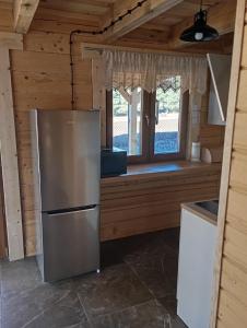 a kitchen with a refrigerator and a window at Apartament Szumi las in Białowieża +2 photos