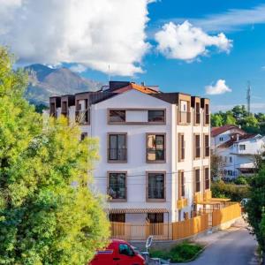un bâtiment blanc avec une voiture rouge garée devant dans l'établissement Tivat Cocoon Studio, à Tivat