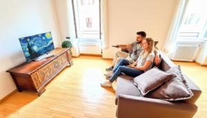 Ein Mann und eine Frau sitzen auf einer Couch im Wohnzimmer in der Unterkunft LUXURY -JACUZZI- FLAT 100mq, elegante e storico, nel borgo medievale in Trient