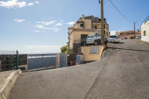 a building with a car parked on the side of a street at Calheta, Sun, Sea & Pool in Calheta