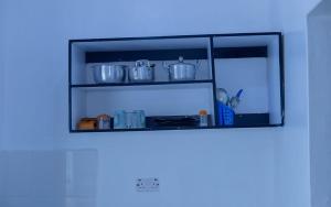 a kitchen shelf with pots and pans on it at Sinty's furnished homes in Narok