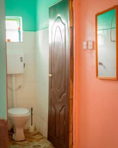 a bathroom with a toilet and a wooden door at Sinty's furnished homes in Narok