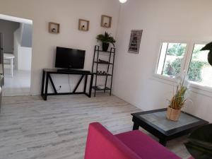 a living room with a tv and a couch and a table at Maison avec jacuzzi et jardin privé, proche plage in Le Pradet