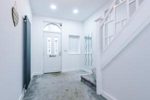 a white hallway with a white door and stairs at 6BR Home - Sleeps 15 - Ideal for Contractors & Group Stays - Parking in Castleton