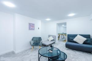 a living room with a blue couch and a glass table at 6BR Home - Sleeps 15 - Ideal for Contractors & Group Stays - Parking in Castleton