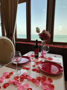 a table with pink roses and glasses and a bottle of wine at Olive Garden Baku Hotel in Baku