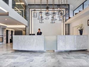 a woman standing behind a reception desk in a lobby at Mercure Rhodes Alexia Hotel & Spa in Rhodes Town +110 photos