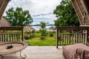 a wooden deck with a bed and a view of the water at Gipsy Beach Bungalows in Sekotong