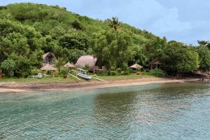 a beach with a house and a boat in the water at Gipsy Beach Bungalows in Sekotong