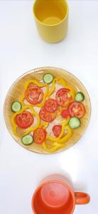 a plate with tomatoes and cucumbers and a bowl and a spoon at Pajama Hostel Nile View in Aswan