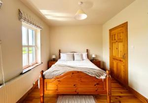 a bedroom with a wooden bed and a window at Wild Atlantic Haven in Ballyferriter