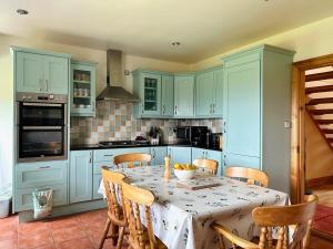 a kitchen with blue cabinets and a table with chairs at Wild Atlantic Haven in Ballyferriter