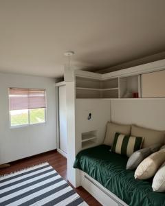 a bedroom with a bed with green sheets and a window at Seara Host in Lages