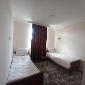 a hotel room with two beds and a window at Hotel Javlonbek 1 in Samarkand