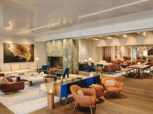 um lobby de hotel com mesas e cadeiras em Fairmont Golden Prague em Praga