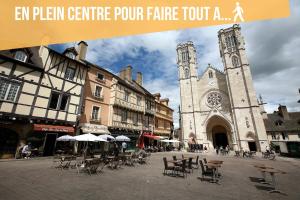 a building with a church with a tower and tables and chairs at Le Goupil in Chalon-sur-Saône