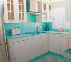 a kitchen with white cabinets and blue counter tops at Alojamiento Oasis Playa in Águilas