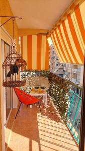 a balcony with a red chair and a table at Alojamiento Oasis Playa in Águilas