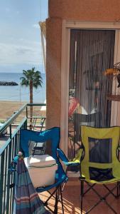 2 stoelen en een tafel op een balkon met uitzicht op het strand bij Alojamiento Oasis Playa in Águilas