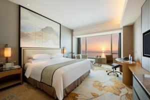 a bedroom with a bed and a desk and a television at Shangri-La Xiamen in Xiamen