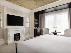 a bedroom with a bed and a tv and a fireplace at Fairmont Windsor Park in Windsor