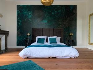 a bedroom with a large bed with a green wall at La Tour du Maine in Marmande