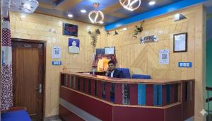 ein Mann sitzt an einer Bar in einem Raum mit einer Holzwand in der Unterkunft Hotel Tirupati Inn Hill View in Shimla