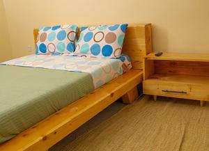a bedroom with a wooden bed with pillows and a table at RP Gorilla Guest & Coffee in Kinigi