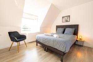 a bedroom with a bed and a black chair at O Ricoul - Maison avec jacuzzi proche Rennes in Corps-Nuds