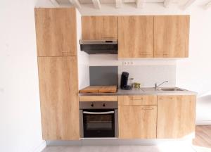 a kitchen with wooden cabinets and a sink at O Ricoul - Maison avec jacuzzi proche Rennes in Corps-Nuds