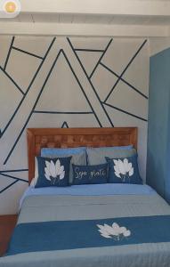 a bedroom with a bed with blue and white pillows at EcoChalé de Arraial in Arraial do Cabo