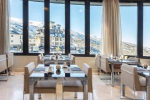 a restaurant with tables and chairs with mountains in the background at Meliá Sol y Nieve in Sierra Nevada