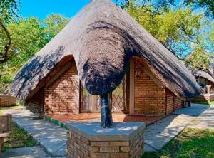 a building with a thatched roof with a statue at Selukwe Safari Lodge in Marloth Park