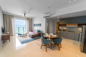 Tanjong TokongにあるPenang Beachfront Seaview Residencesのキッチンとテーブルと椅子のあるリビングルーム