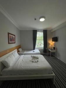 Una habitación de hotel con dos camas y una ventana. en Princes Palace, en Londres