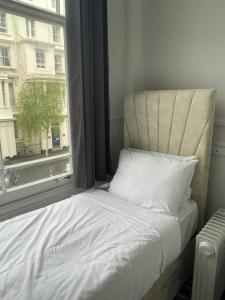 Una cama sentada en una habitación con ventana. en Princes Palace, en Londres