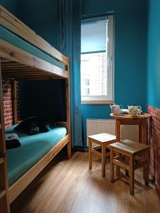 a bedroom with a bunk bed with a table and a bench at Jopi Hostel Katowice Centrum in Katowice