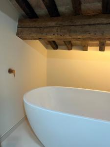 a white bath tub in a bathroom with wooden ceilings at Can Los arcos in Chioggia +16 photos