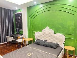 a bedroom with a green wall with a bed and chairs at Venus apartment 45 in Hanoi