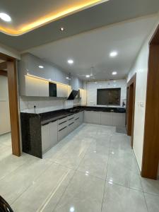 Una cocina grande con gabinetes blancos y piso de baldosas. en Home away from Home close to Swaminarayan Temple, en Nadiād