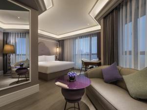 a hotel room with a bed and a couch and a table at Mercure Nantong Downtown in Nantong